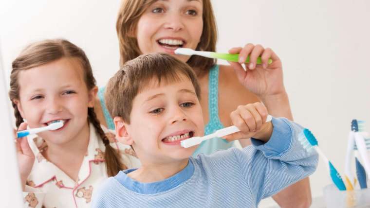 Persona realizando una rutina completa de higiene oral frente al espejo.
