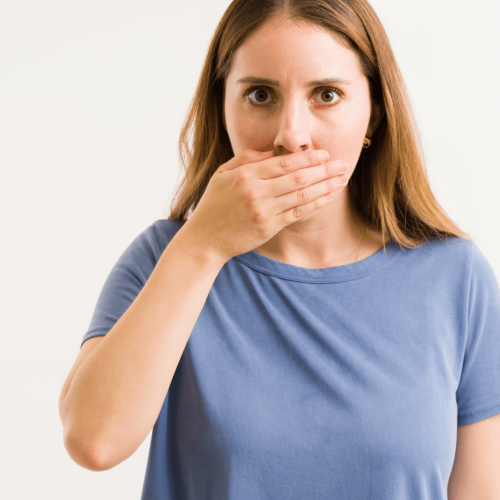 Persona preocupada por tener mal aliento a pesar de cepillarse los dientes