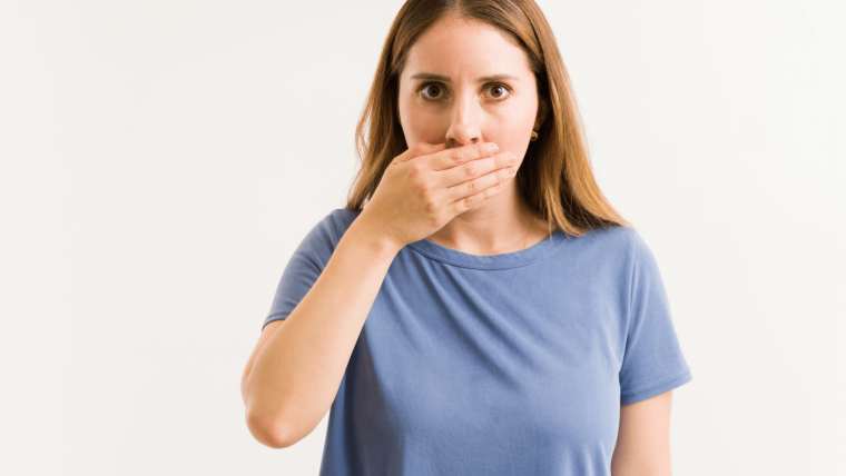 Persona preocupada por tener mal aliento a pesar de cepillarse los dientes